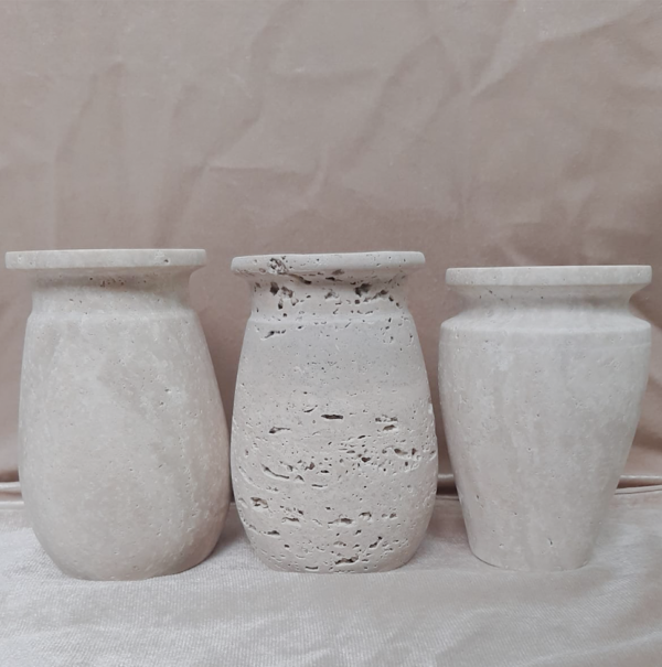 Set of three elegant travertine marble vases with a natural, textured finish.